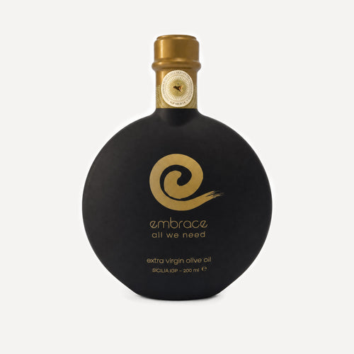 200ml bottle of Embrace All We Need Extra Virgin Olive Oil in a distinctive rounded black bottle with a gold cap and gold logo, set against a light gray background.