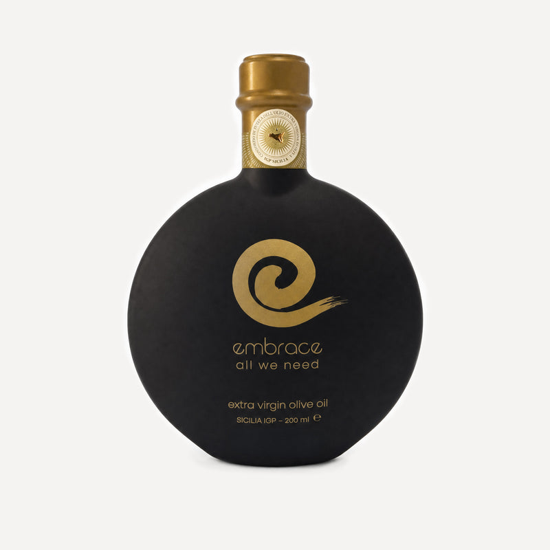 200ml bottle of Embrace All We Need Extra Virgin Olive Oil in a distinctive rounded black bottle with a gold cap and gold logo, set against a light gray background.