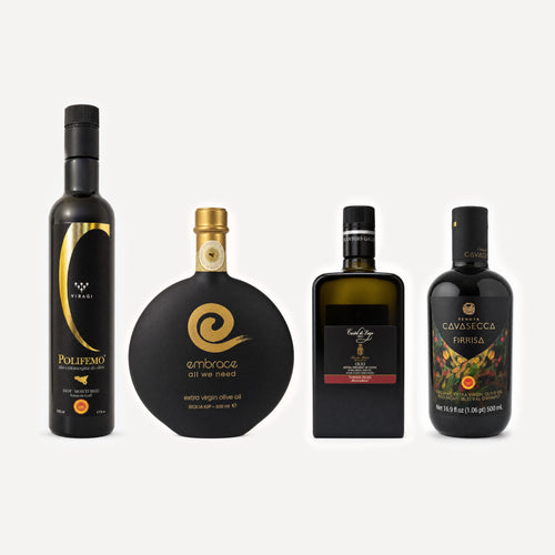 Four bottles of olive oil arranged side by side on a light gray background: a tall black bottle with gold lettering on the left, a round matte black bottle with a gold spiral logo in the center, a dark rectangular bottle with a black label, and a black bottle with gold and orange graphics on the right.