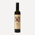 A dark glass bottle of Sbezi Extra Virgin Olive Oil with a black cap and a beige label featuring a colorful geometric pattern, set against a light terracota background.