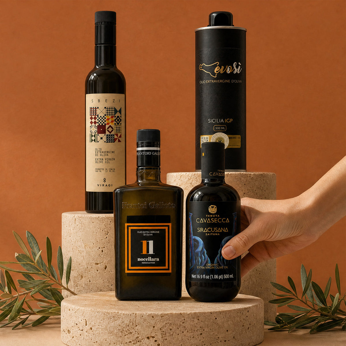 Four separate olive oil bottles on stone blocks against a terracotta background
